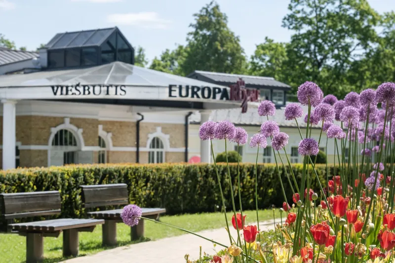 Hotel facade behind flower beds of tulips and alliums in summer