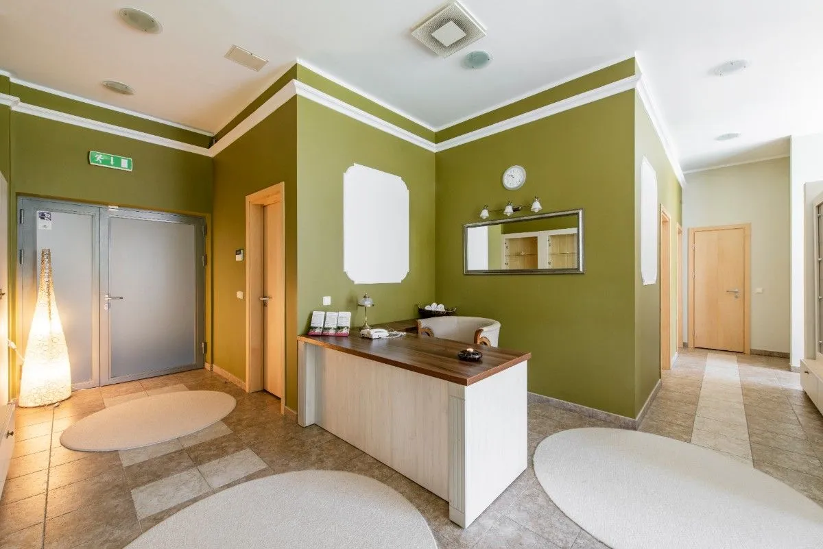Spa corridor with olive green walls, a washbasin and treatment room doors