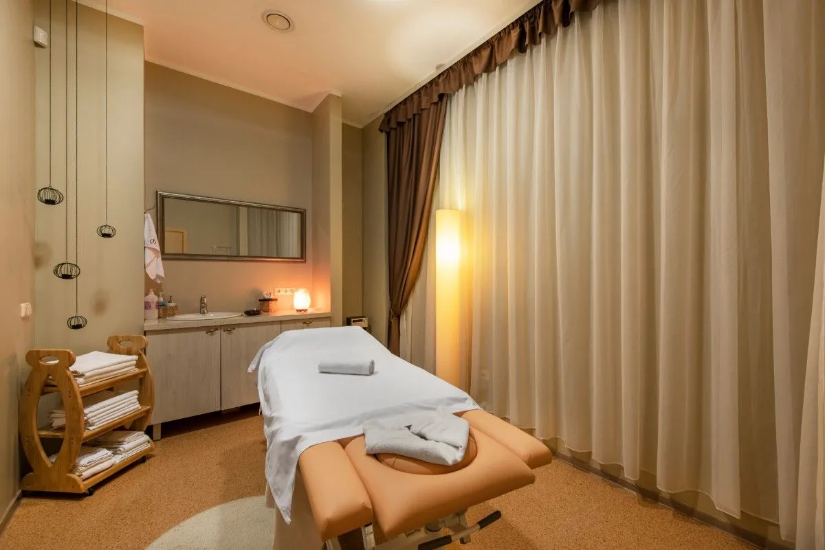 Treatment room with a massage table, folded towels and a curtained wall