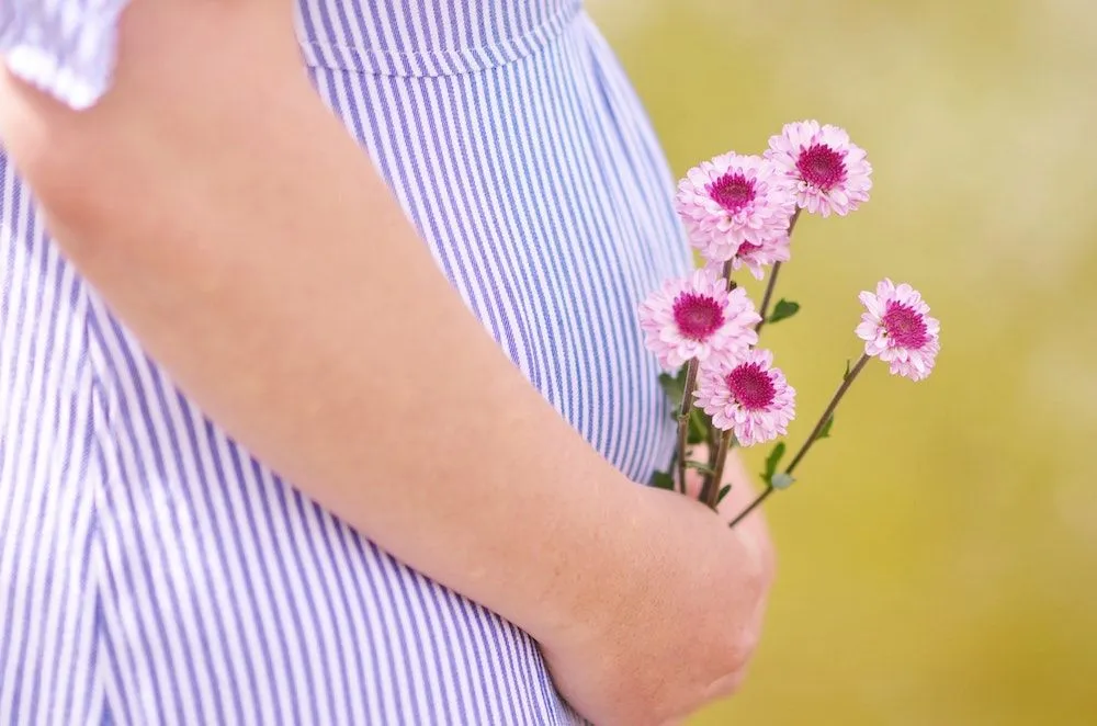 Pregnant woman in a striped dress holding a small posy of flowers