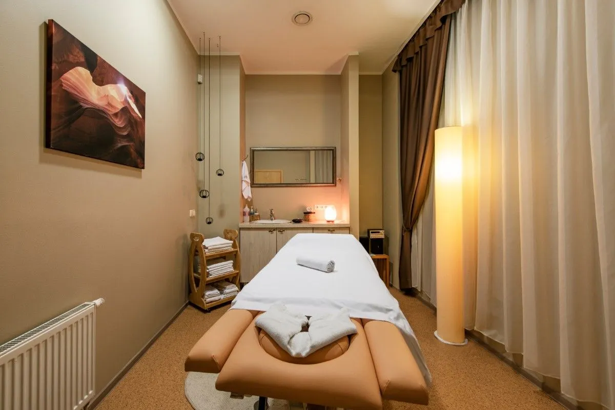Treatment room with a massage table, warm lighting and a framed picture