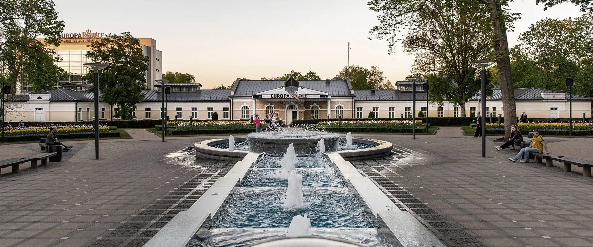 Park fountains and cascades leading to a white historic building at dusk