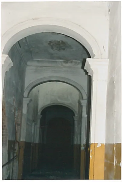 Vaulted interior passage with peeling plaster before restoration