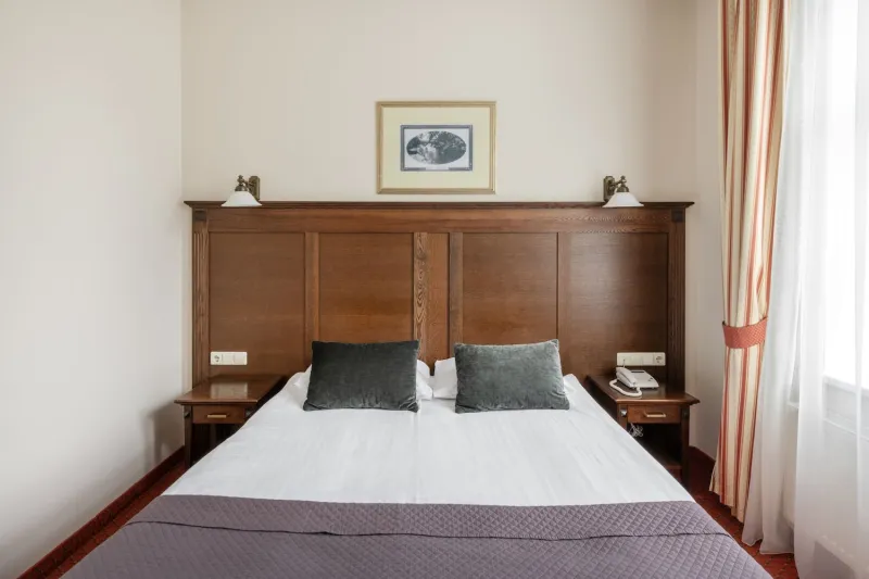 Double bed with a wooden headboard, two reading lamps and a framed picture on the wall above