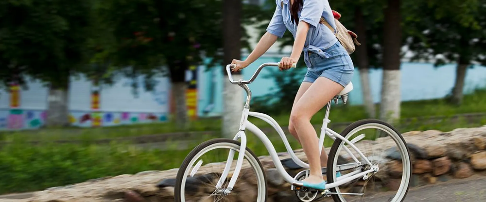 Woman cycling along a paved path through a green park in Druskininkai