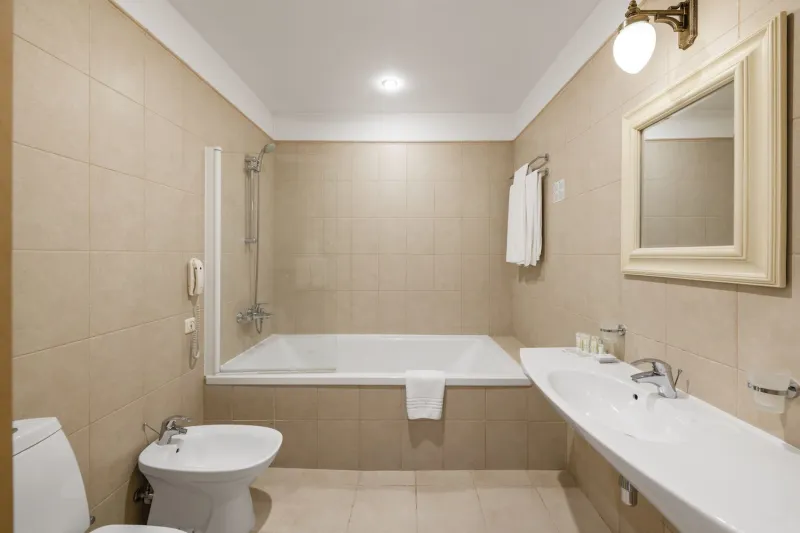 Bathroom with a bathtub and glass screen, washbasin, mirror, hanging towels and a bidet