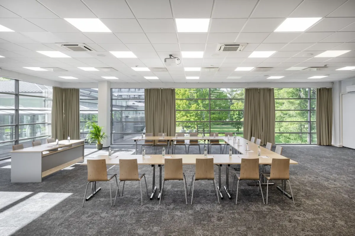 Conference room set in a U-shape with a full-height window onto greenery