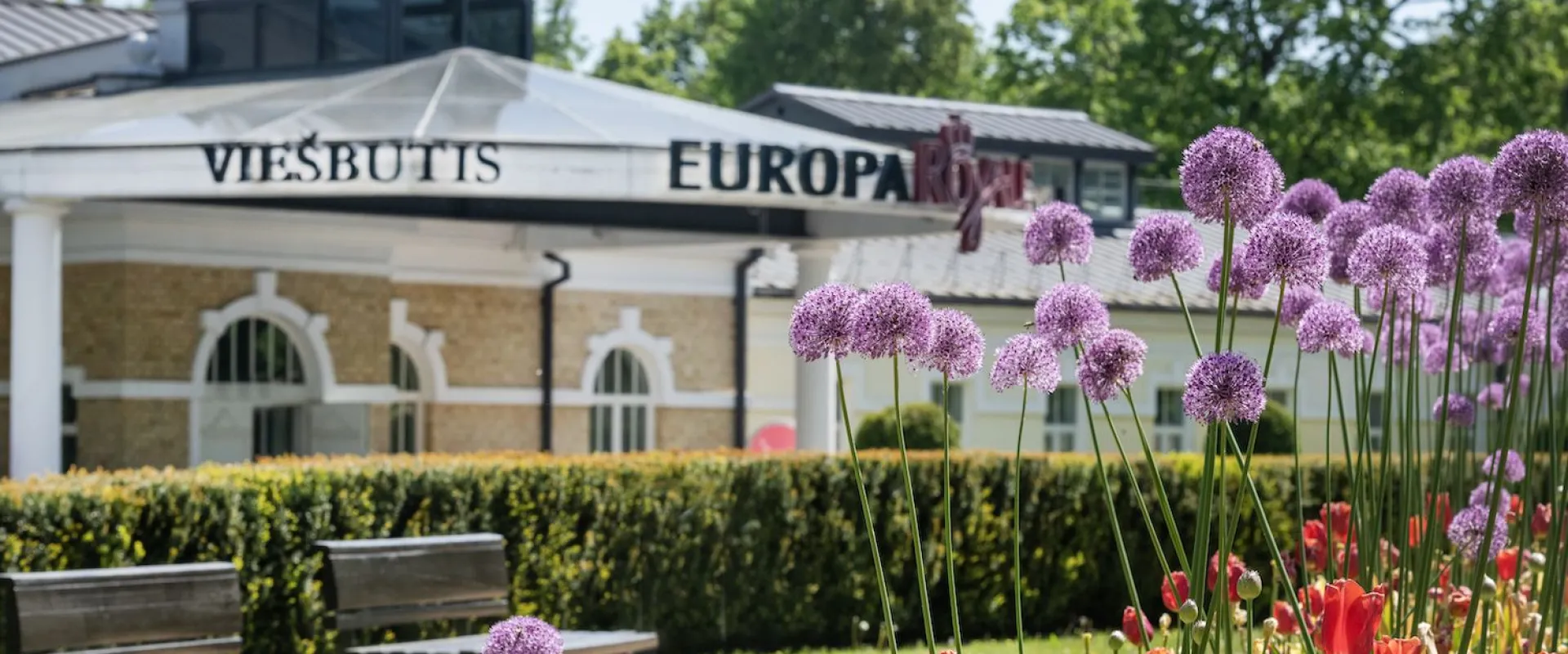 Hotel facade behind flower beds of tulips and alliums in summer