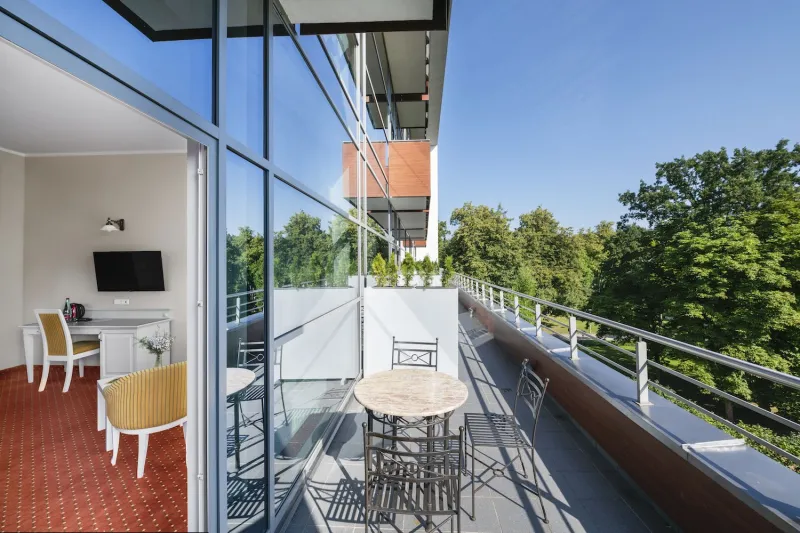 Balcony with wrought-iron cafe tables and chairs overlooking the treetops