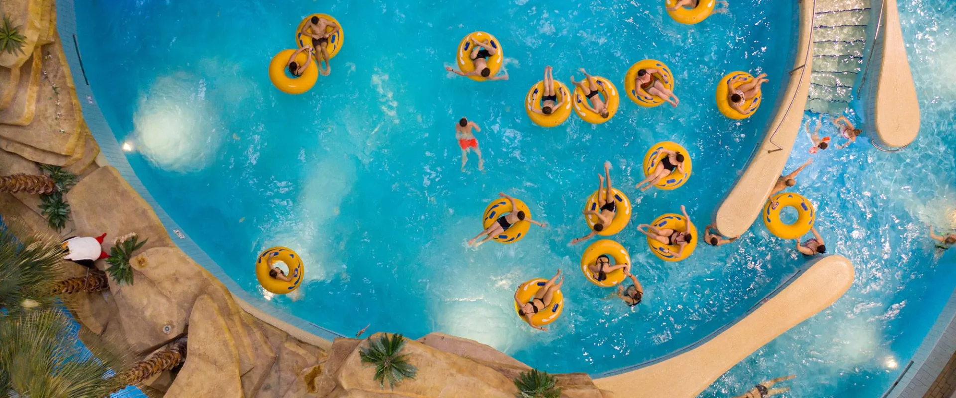 Water park pool seen from above with guests floating on yellow rings