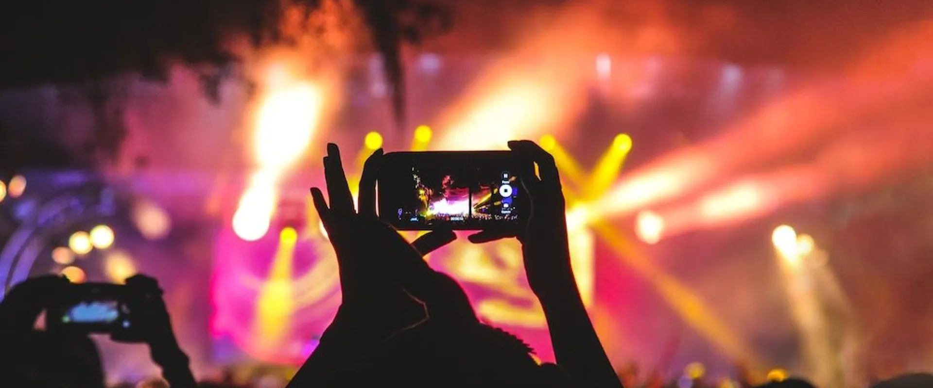 Festival crowd filming a brightly lit stage on their phones
