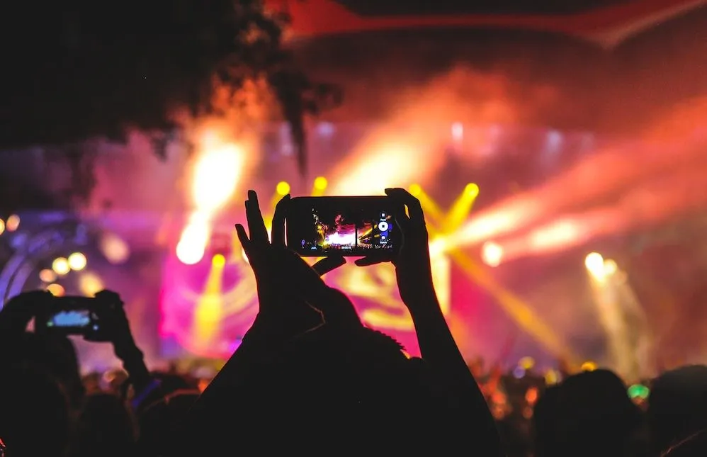 Festival crowd filming a brightly lit stage on their phones