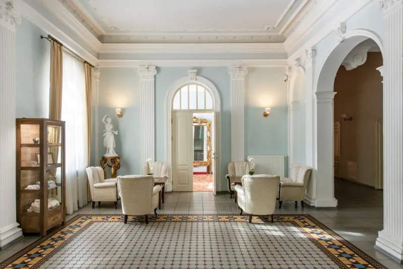 Hotel lounge with pale blue walls, armchairs and a patterned mosaic floor