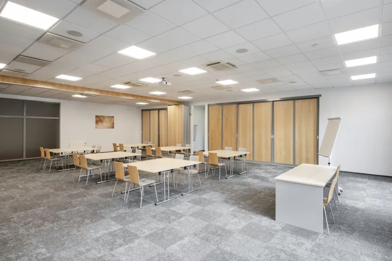 Meeting room with tables in a classroom layout and a flip chart