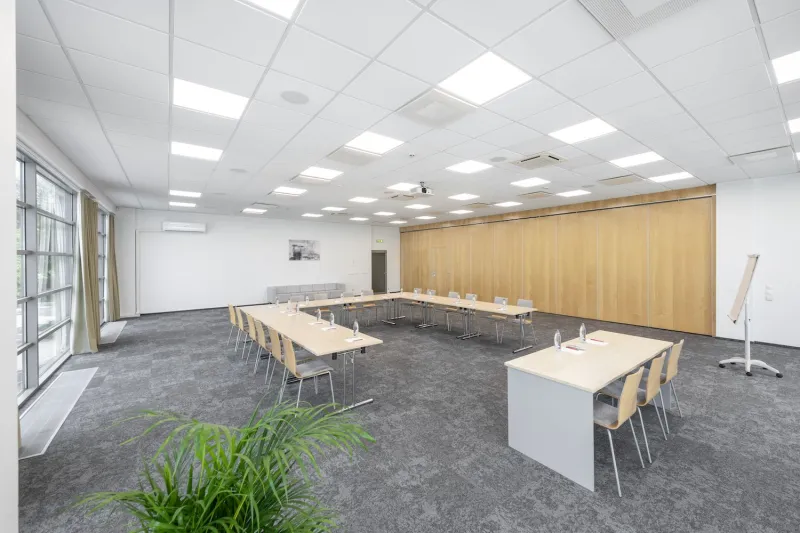 Meeting room with tables in a U-shape and a flip chart by the window