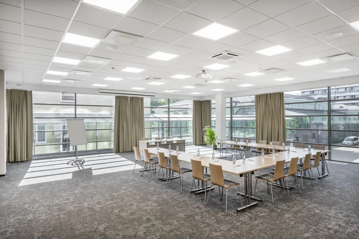 Bright meeting room with a U-shaped table and windows on two sides