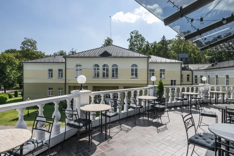 Terrace with cafe tables and a balustrade overlooking the spa building