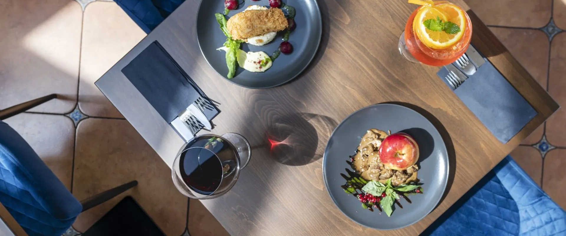Two plated dishes seen from above with wine and a spritz